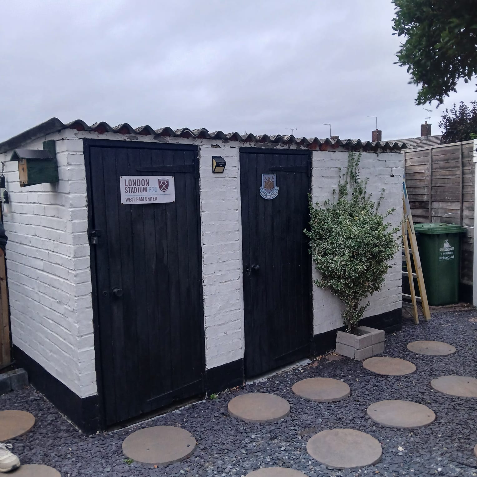 White brick garage with black double doors standing in a gravelled Essex garden